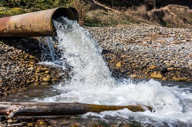 An image showing water gushing out of a wastewater pipe into a river