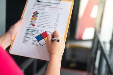 Someone fills in a hazardous chemical safety checklist on a clipboard