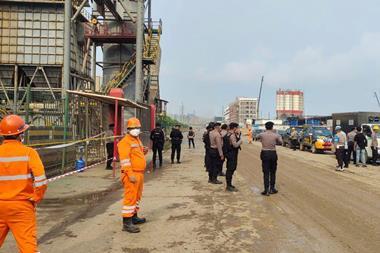 In Indonesia, uniformed police officers and workers in safety equipment at an industrial plant