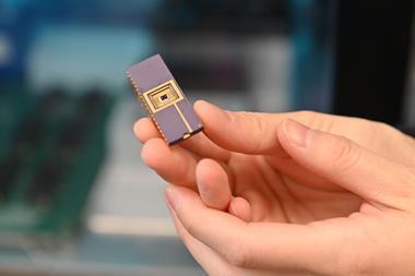A hand holding a small microchip-style sensor