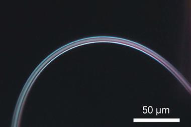 An image of a thin, blue-white filament forming an arch on a black background
