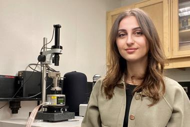 A photograph of Alaa Al-Shaer standing in front of a microscope