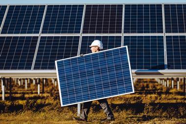 A photo of a worker carrying a solar panel