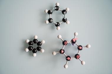 Three benzene ball and stick models arranged on a grey background