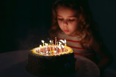 A picture of a little girl blowing candles on her birthday cake