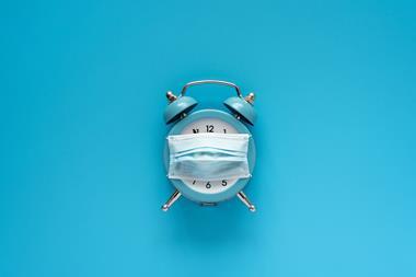 An image showing an alarm clock with a face mask on