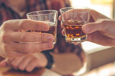 An image of two men clinking whiskey glasses