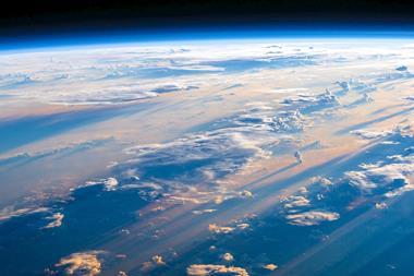 An outer-space view of earth, showing layers of clouds over a blue ocean. The planet's curvature can be seen in the distance before the deep-black background of space.