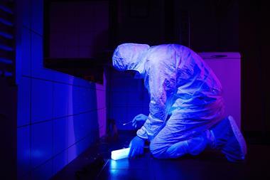 Technician collecting DNA evidence on place of crime under UV black light