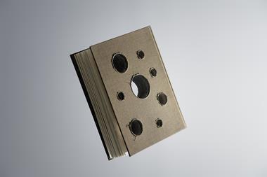 A brown hardback book with several holes that penetrate its full thickness