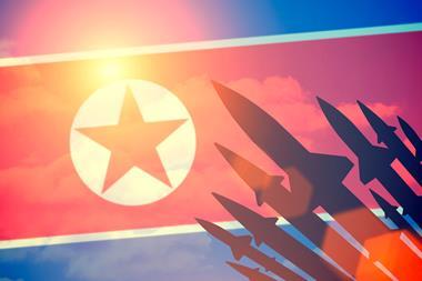 Rocket silhouettes against a background of the flag of North Korea