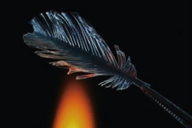 An photo of a transparent glass feather held over a flame