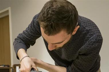 A researcher using a piece of technology to analyse some old books with green covers