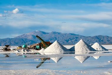 A working lithium mine with piles of salt and a view of the Andes mountain range behind