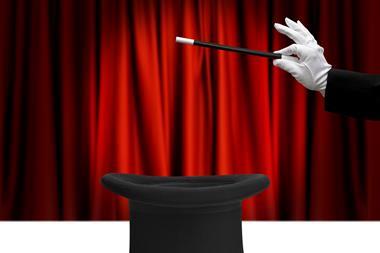 An image showing a magician's hand hovering a wand on top of a top hat