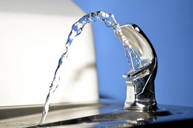 Close up of a public drinking fountain with a spout of water flowing out