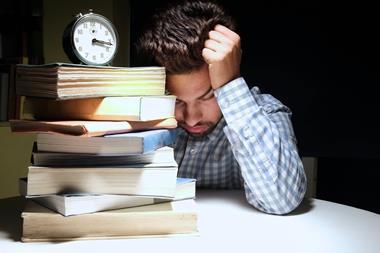Stressed student working through a pile of books