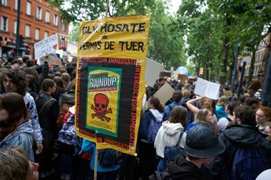An image showing a protester holding a placard reading 'Glyphosate : license to kill'