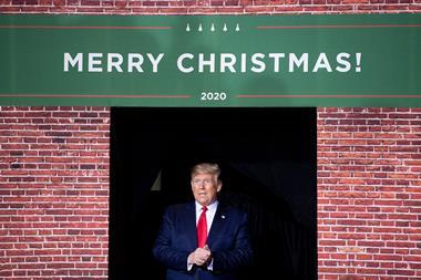An image showing Donald Trump next to a Merry Christmas sign