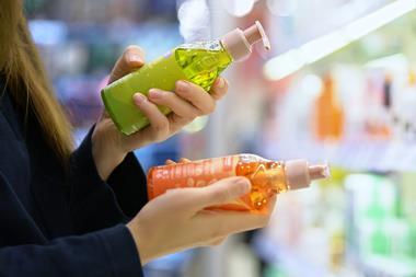 Woman examining two cosmetics bottles