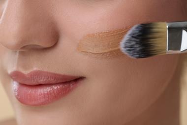 Close up of a woman's face applying foundation with a brush