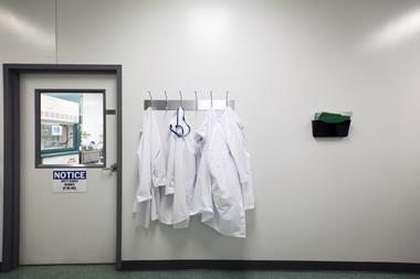 Closed door to laboratory with lab coats hanging from coat rack