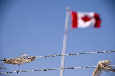 The Canadian flag behind barbed wire