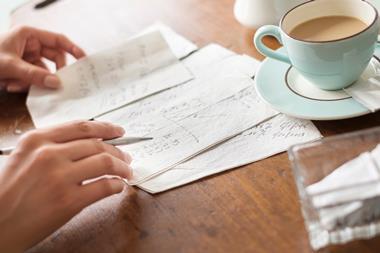 Someone having a cup of tea while doing calculations on a napkin