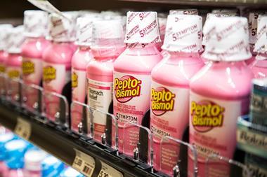 A row of Pepto-Bismol bottles with their bright pink contents lined up on a shelf