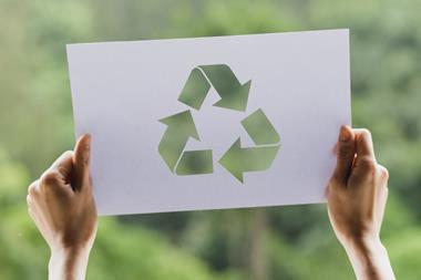 Hands holding sign with recycling symbol on it