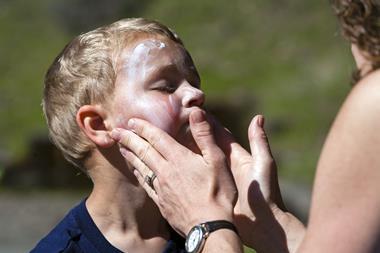 boy having sunscreen applied to his face by his mother