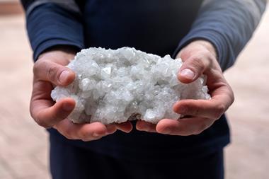 Pair of hands holding a white aggregate rock of crystals