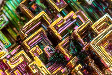 Bismuth crystals close up, geometric swirls of green yellow and purple