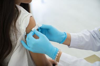 Doctor applies bandage to preteen girl's arm following an immunization