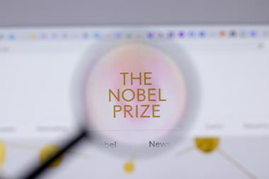 A magnifying glass looking at a computer screen showing the Nobel Prize website