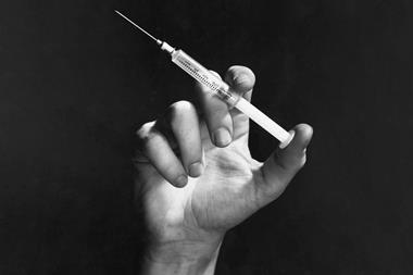 An image showing a hand holding a hypodermic needle