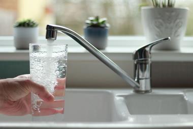 A hand filling a glass of water from a kitchen tap