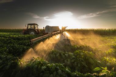 Tractor spraying glyphosate at sunset