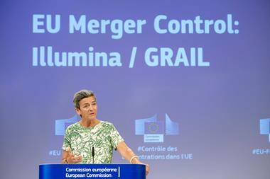 A woman speaking at an European Commission lecture. Behind her is a large projected slide which says EU Merger Control: Illumina / GRAIL