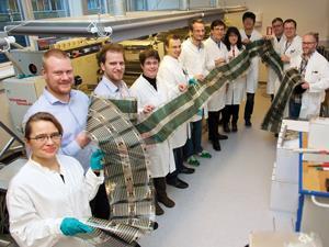 scientists holding long flexible solar cell