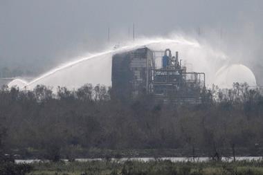 Firefighters douse the exterior of a chemical plant with water after a fire following a storm