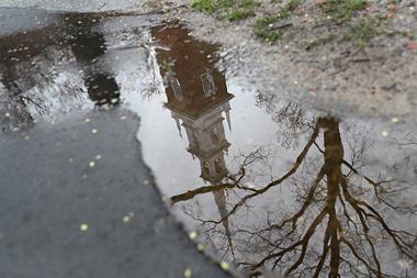 An image showing how the Memorial Church in Harvard Yard is reflected in a puddle on an empty campus at Harvard University