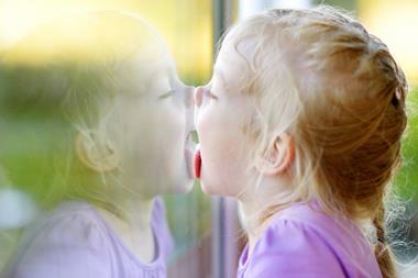 Girl licking her reflection on a window glass