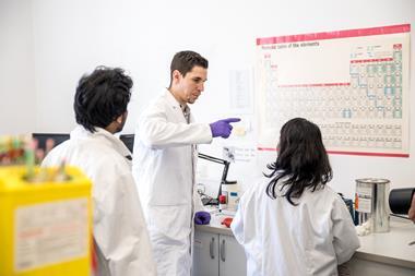 A scientist giving instructions to two other scientists in a lab