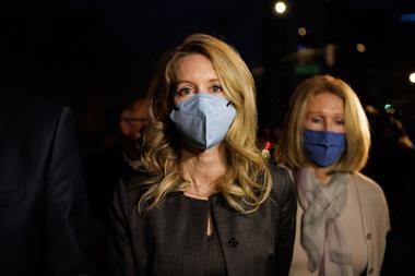 Elizabeth Holmes wearing a face mask and business suit leaving court