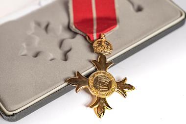 A gold cross shaped medal with a red ribbon