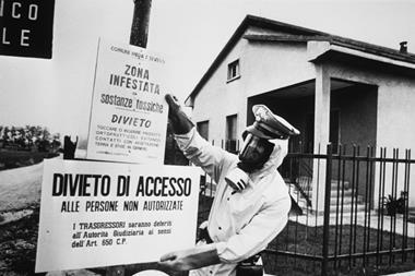 An official in protective clothing places warning signs following the Seveso disaster in 1976