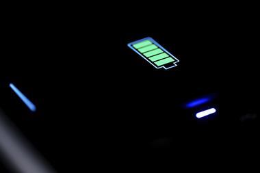 A close-up of a green battery charging icon on a dark phone screen