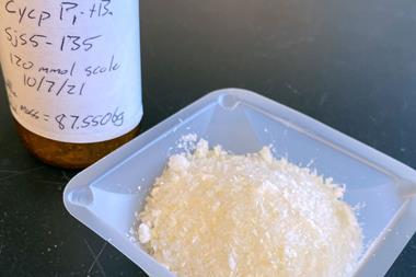 A sample of white crystals next to a bottle with a handwritten label