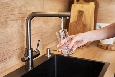 Hand holding glass filling with tap water